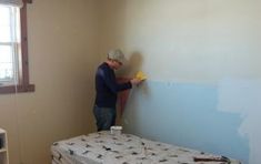 a man is painting the walls in his bedroom