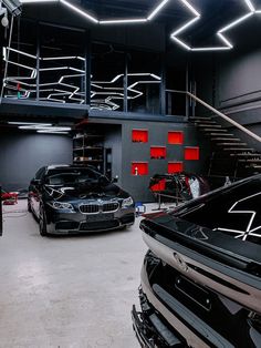 two cars parked in a garage with stairs leading up to the top floor and below them