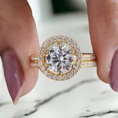 a woman's hand holding a ring with a diamond in the center and two rows of diamonds around it