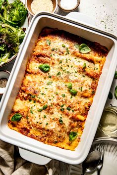 a casserole dish with cheese and spinach on the side next to other dishes