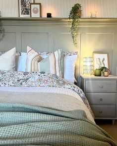 a bed with pillows and blankets on top of it next to a dresser in a bedroom