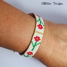 a woman's arm wearing a bracelet with red, green and white beads on it