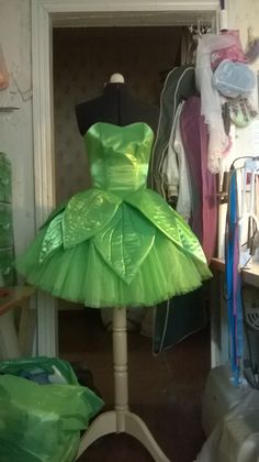 a green dress sitting on top of a mannequin in a room filled with clothes