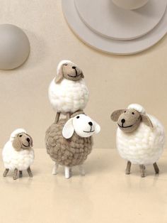 three sheep standing next to each other in front of a white wall and ceiling light