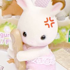 a white stuffed animal holding a wooden stick in its paws and wearing a pink dress