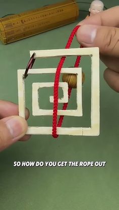 two hands are working on an ornament with yarn and thread in the shape of a square