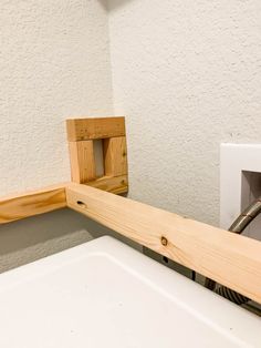 a bathroom sink under a wooden shelf next to a wall mounted air freshener dispenser