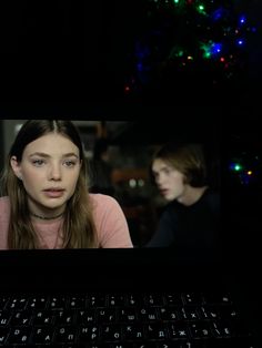 a young woman sitting in front of a laptop computer with the screen lit up at night