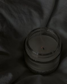 a candle sitting on top of a black cloth next to a glass jar filled with liquid