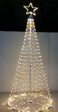 a lighted christmas tree in the middle of a room with white walls and flooring