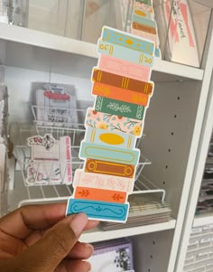 a person holding up a stack of stickers in front of a book shelf filled with books