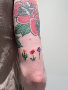 a person with a flower and cactus tattoo on their arm, holding onto a cell phone