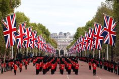 a group of people in red uniforms marching down a street with flags on either side