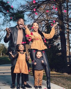 a family poses for a photo on the sidewalk with hearts flying in the air above them