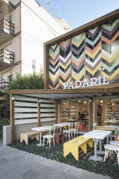 an image of a restaurant with colorful stripes on the wall and tables in front of it