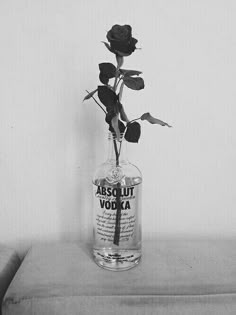 a black and white photo of a rose in a vodka bottle