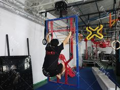 a man is climbing up on a ladder in a gym with other equipment around him