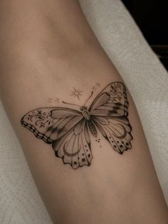 a black and white butterfly tattoo on the left arm, with stars in the background