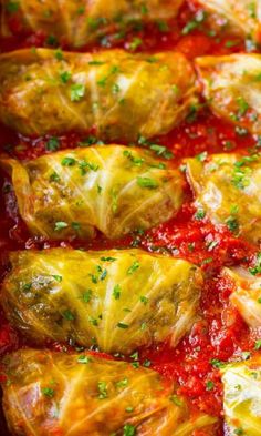 stuffed cabbage rolls with marinara sauce and parsley on top in a casserole dish