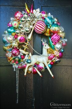 a christmas ornament wreath hanging on a door with ornaments around it and a deer figurine in the center