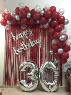 balloons and streamers decorate the entrance to a 30th birthday party with red, white and silver decorations