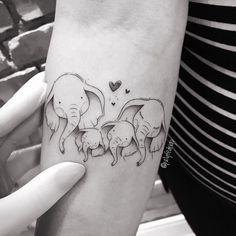 a woman holding her arm with three elephants on it and a heart in the background