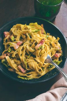 a black bowl filled with pasta and broccoli