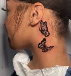 a woman's neck with two butterflies on the back of her head and behind her ear