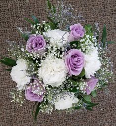 a bouquet of white and purple flowers sitting on top of a brown carpeted floor