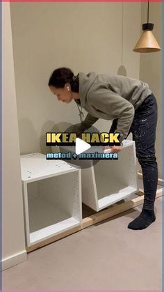 a woman in grey sweater and black boots working on white shelving unit with ikea rack