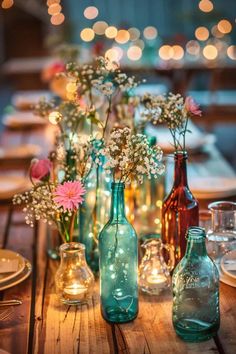 several vases filled with flowers sitting on top of a wooden table covered in lights