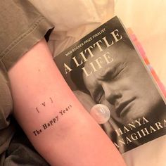 a person with a tattoo on their arm next to a book