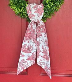 a red door with a white bow hanging from it's side