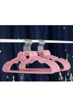 three pink clothes hangers on a blue curtain with white stars in the sky behind them