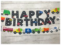 a happy birthday banner with trucks and cars on it, hanging from the side of a wooden wall