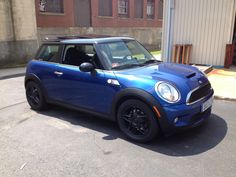 a small blue car parked in front of a building