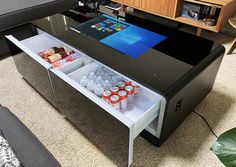 a coffee table with an open drawer underneath it and drinks on the bottom shelf below