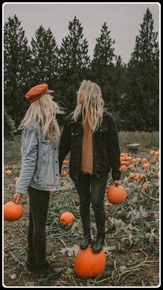 two women standing in a field with pumpkins