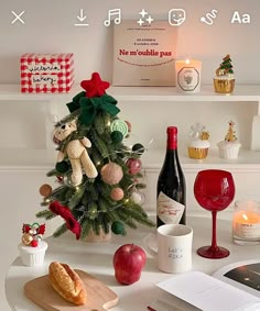 a small christmas tree sitting on top of a table next to wine glasses and other items