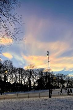 people are walking in the snow at sunset