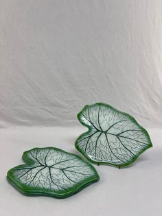 two green leaf shaped dishes sitting on top of each other