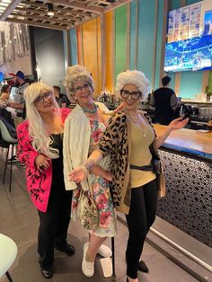 three women standing next to each other in front of a bar