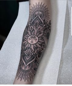 a black and white tattoo on the leg of a person with an intricate sun design