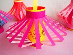 pink and yellow vases are sitting on a table with paper decorations in the background