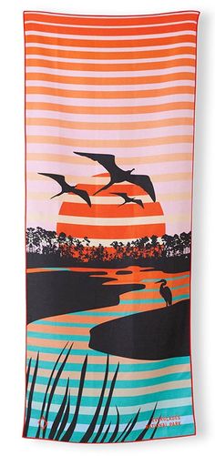 a beach towel with two birds flying over the water and trees in the background at sunset