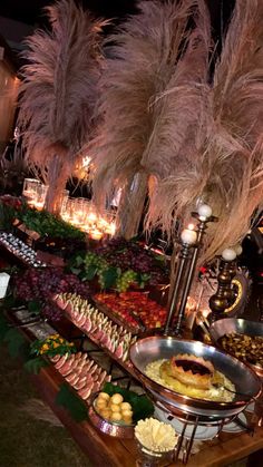 an assortment of food is displayed on a buffet table with tall pamolite grass in the background