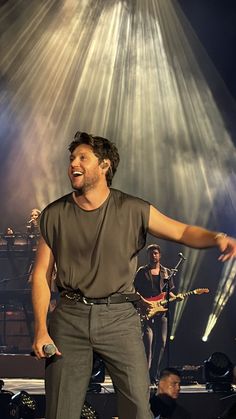 a man standing on top of a stage with his arms out in front of him