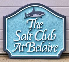 a sign for the salt club at belaire with a shark on it's side