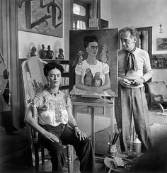 an old black and white photo of two people in front of art on easels