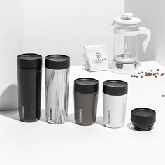 the coffee cups are lined up on the counter next to the blender and grinder